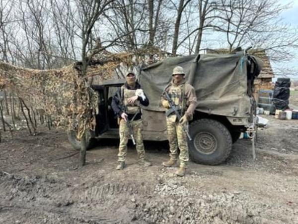 Ukrainian soldiers Kotya and Sova with one of the dogs that lives with them on the Robotyne front.